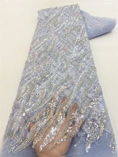 a woman's hand is covered in sequins and beads on a blue cloth