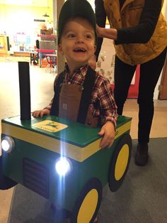 a young boy is sitting in a toy train with lights on his head and smiling at the camera