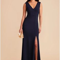 a woman in a long blue dress with a slit down the side and a gold clutch