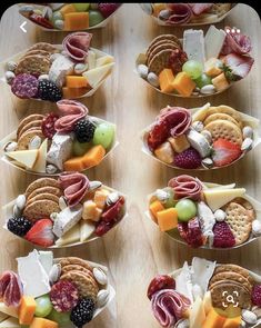 many small bowls filled with different types of cheeses and crackers on top of a wooden table