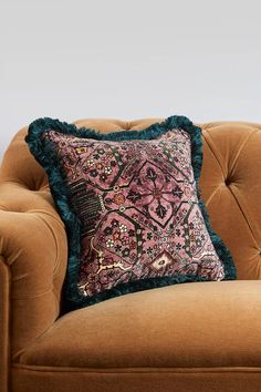 a brown couch with a pink and blue pillow on it