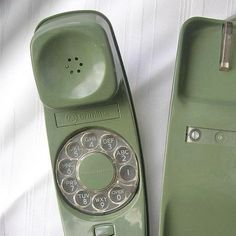 an old green phone sitting on top of a white sheet