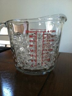 a measuring cup filled with ice on top of a wooden table