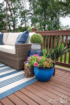 an outdoor patio with wicker furniture and potted plants on the decking area