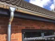 a metal gutter attached to the side of a brick building