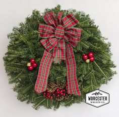 a christmas wreath with red berries and pine cones