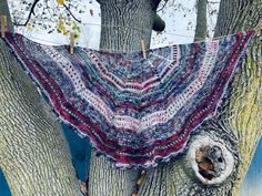 a crocheted shawl hanging from a tree