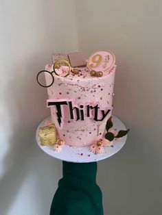 there is a pink cake with the word thirty on it and other things sitting on top