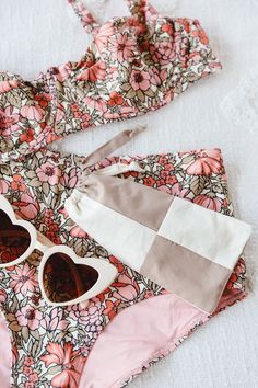 two pieces of clothing on top of a bed with pink and white floral print material