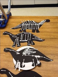 three paper cut out dinosaurs on a table