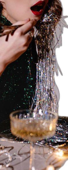 a woman is pouring champagne into a glass on a table with confetti in it