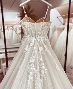 a dress on display in a store with other wedding gowns behind the mannequin