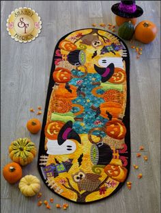 an orange and black table runner with pumpkins on the floor next to it,