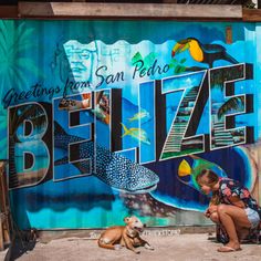 a woman and her dog sitting in front of a wall painted with the words breeze