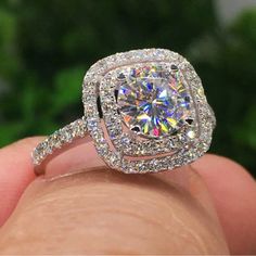 a close up of a person's hand holding an engagement ring with a large diamond in the center