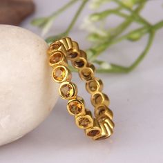 two gold rings sitting next to each other on top of a white rock with flowers in the background