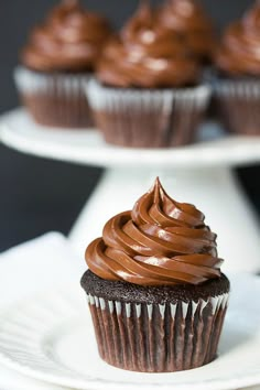 cupcakes with chocolate frosting on two white plates