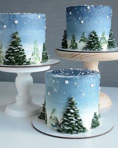 three cakes decorated with trees and snow on them