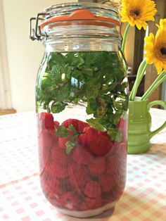 a mason jar filled with strawberries and green leaves