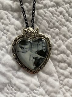 a heart shaped necklace with an old photo on it