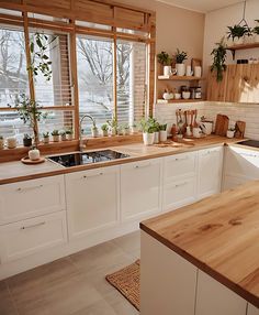 a kitchen filled with lots of wooden counter tops and white cabinets next to a window