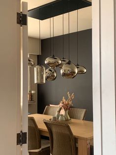 a dining room table with chairs and lights hanging from it's ceiling in front of an open doorway