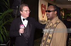 two men in tuxedos are talking to each other at an awards event stock photo