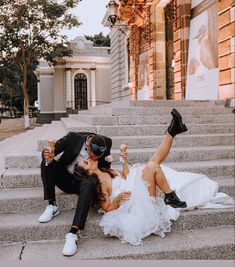 a bride and groom sitting on the steps in front of an old building drinking champagne