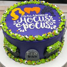 a purple and green birthday cake decorated with halloween decorations on a white platter that says it's all a bunch of hoccuss spooks