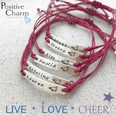 four personalized bracelets with names and hearts on red string, sitting on a white background