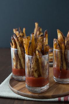 french fries with ketchup in small glass cups on a wooden tray, ready to be eaten