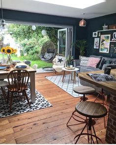 a living room filled with furniture next to a window covered in sunflowers and plants