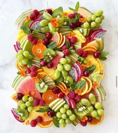 a platter filled with lots of different types of fruits and veggies on top of a white marble counter