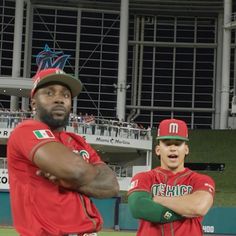 two baseball players are standing on the field with their arms crossed and one is wearing a hat