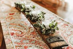 some flowers and candles are sitting on a long piece of wood that is laying on top of a table