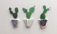 three small ceramic plants sitting next to each other on a white surface with beading around them