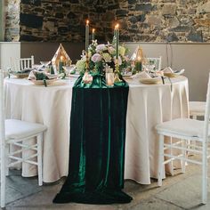 the table is set with white and green linens, silverware, candles, and flowers