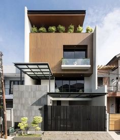 the house is made up of two stories and has plants growing on the top floor