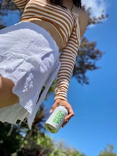 a woman in striped shirt and white skirt holding a can