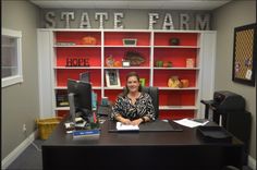 a woman sitting at a desk in front of a red bookcase with state farm written on it