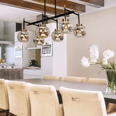 a dining room table with chairs and a vase filled with flowers on top of it