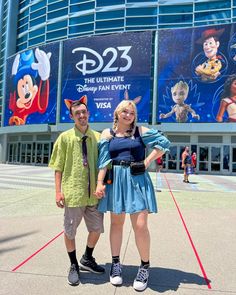 two people standing in front of a building with animation characters on the wall behind them