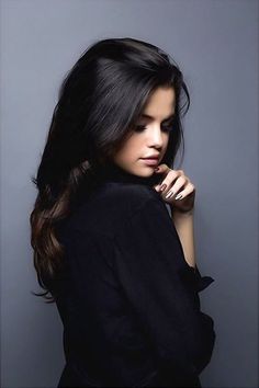 a woman with long dark hair is posing for the camera and looking to her left