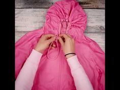 a person tying a pink jacket on top of a wooden floor