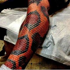 an orange and black snake skin tattoo on the arm