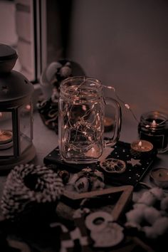 a glass jar filled with candles next to other items on top of a wooden table