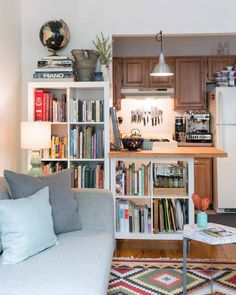 a living room filled with furniture and bookshelves next to a white refrigerator freezer