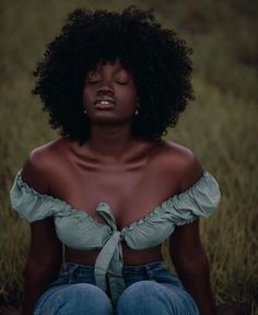 a woman sitting in the grass with her eyes closed