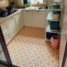 a kitchen with an orange and blue flooring in the middle, next to a stove top oven