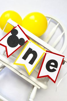 mickey mouse birthday banner with yellow and red balloons on white rocking chair in front of it